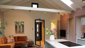 Een moderne woonkamer met een bank, een salontafel, en een eethoek met stoelen en een tafel. Er is een keuken met een aanrecht en een spoelbak.