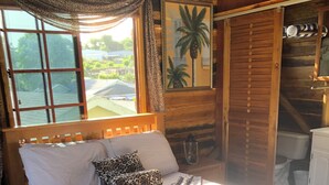 A wooden bed with a white and leopard print bedspread, a swan-shaped pillow, and a window with a view of greenery.