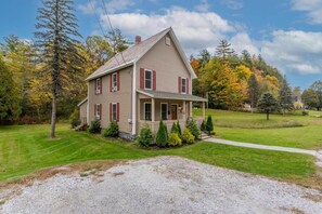 A two-story house with a front porch, surrounded by a well-maintained lawn and trees. - Feel the real VT! Lakes, hikes, a foodies delight! (Proctor)