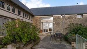 A building with a stone facade, a large glass door, and a patio area with outdoor furniture.