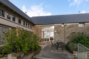 A building with a stone facade, a large glass door, and a patio area with outdoor furniture.
