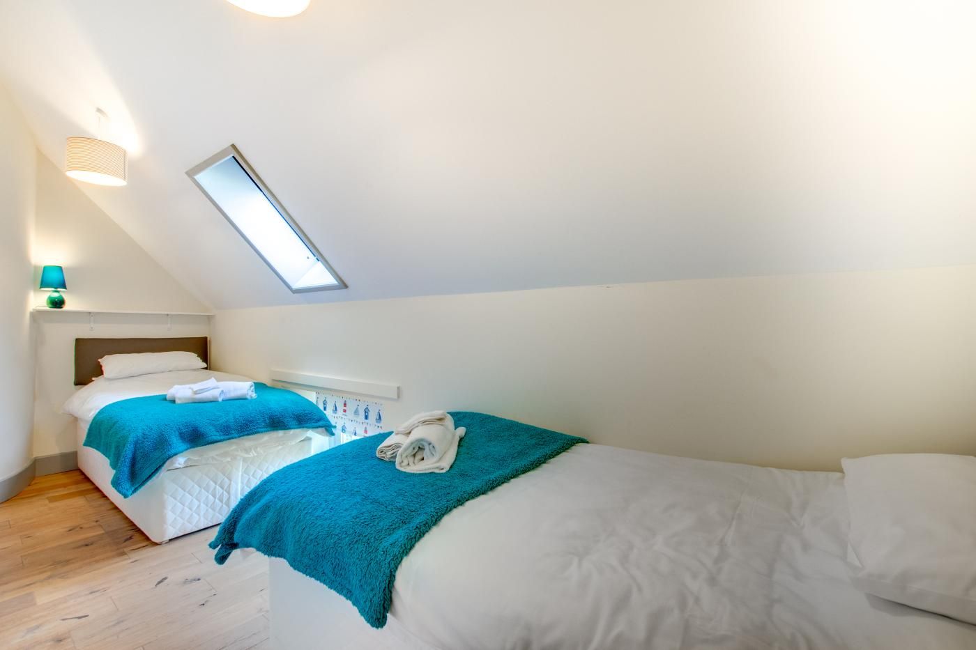 Een slaapkamer met twee bedden, een dakraam en een klein raam.