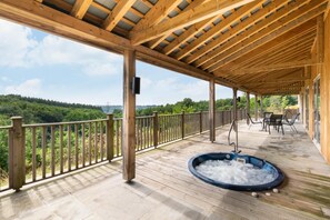 A covered outdoor area with a hot tub, wooden deck, and a view of a forested landscape. - 3 Bed in Totnes (oc-bcdart) (Broadhempston)