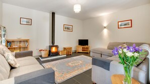 A living room with a fireplace, sofas, a television, and a bookshelf.