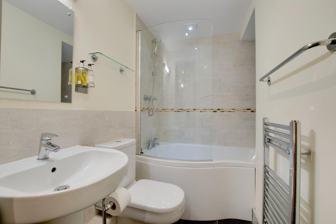 Et moderne badeværelse med vask, toilet og brusekabine med glasvægge.