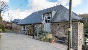 A stone building with a sloped roof, a small porch, and solar panels on the roof. - 3 Bed in Totnes (oc-bcplym) (Broadhempston)