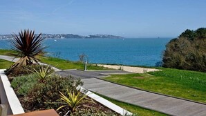 Une vue sur la côte, avec une promenade dallée, des espaces verts et une ligne de rivage visible au loin.