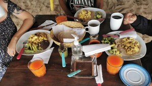 Ein Holztisch mit verschiedenen Speisen, Getränken und Besteck, wahrscheinlich für eine Mahlzeit gedeckt.