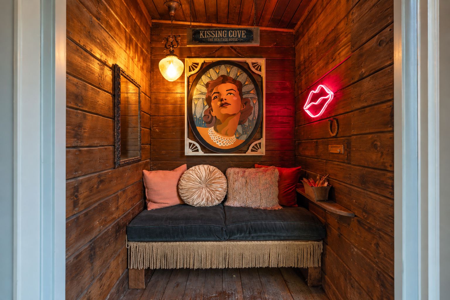 L’intérieur chaleureux d’un chalet avec un banc en bois, un panneau lumineux au néon et une œuvre d’art encadrée.