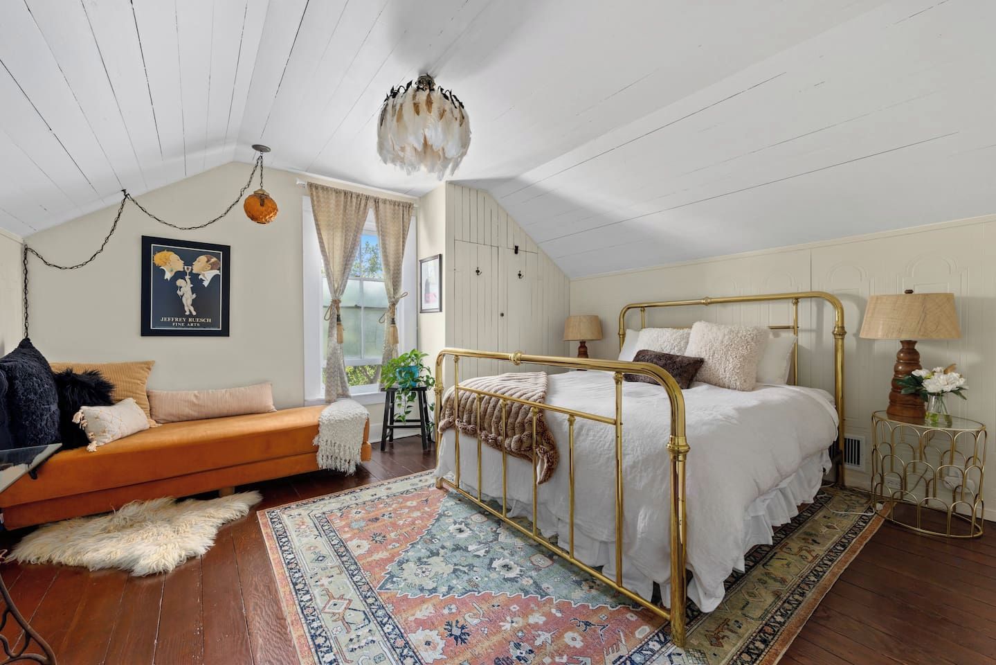 Een slaapkamer met een bed, een bank, een vloerkleed en een hanglamp.