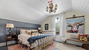 Een slaapkamer met een hemelbed, een kroonluchter, een schilderij van een koe en een raam met gordijnen.