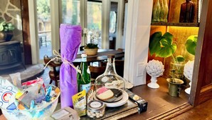 A dining area with a table set for a meal, including a bottle of olive oil, a box of pasta, and a glass of water. - 1882 Heritage House ~ Porches, Gardens & Bali Bed (Los Alamos)