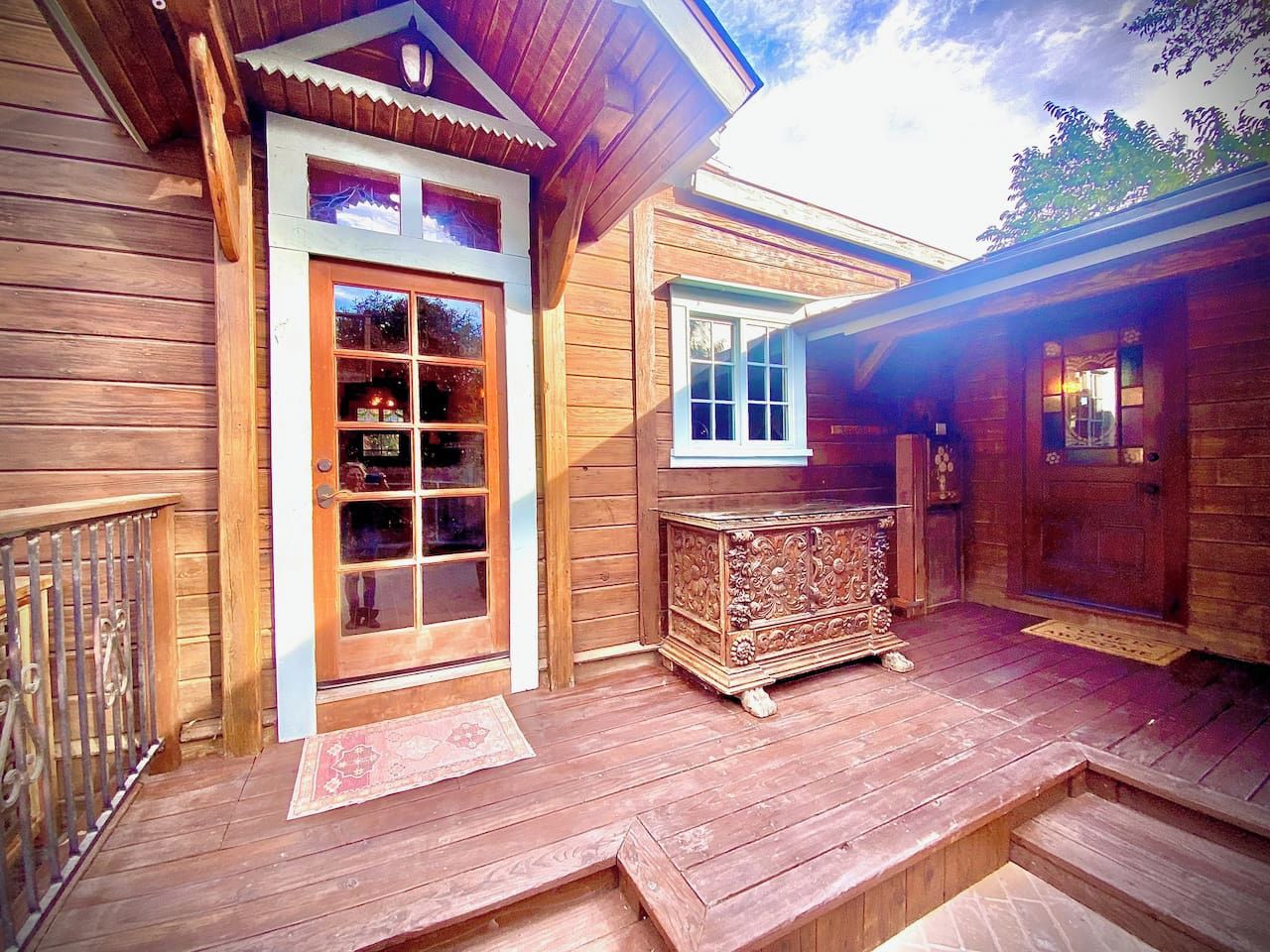 A wooden cabin with a porch, a large glass door, and a small cabinet.
