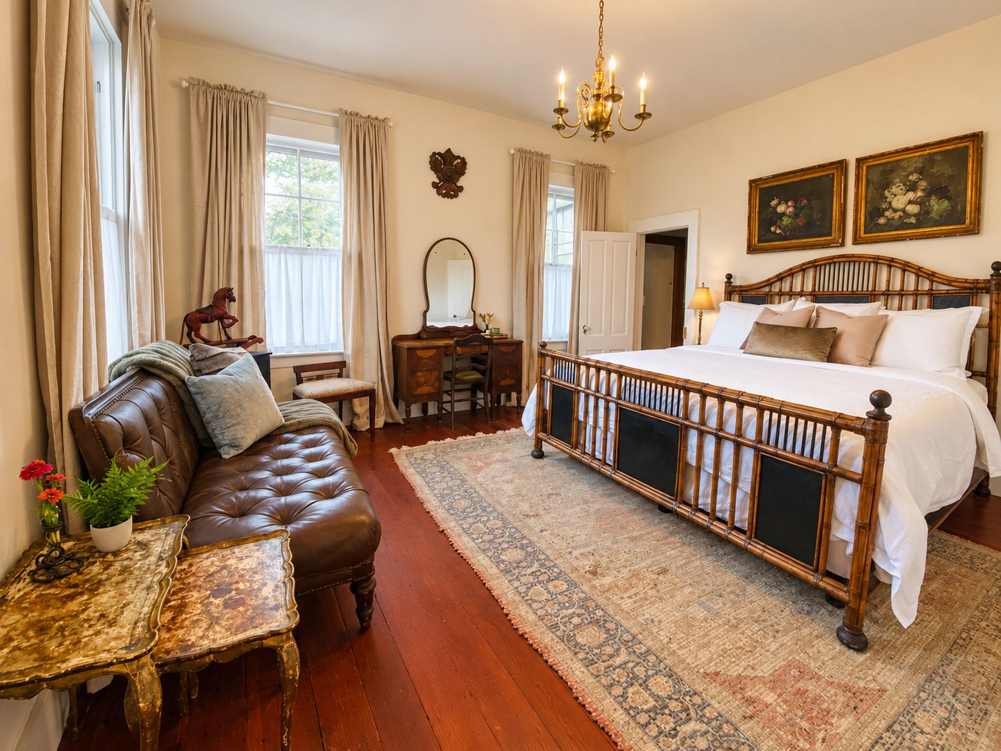 A bedroom with a large bed, a leather sofa, a desk, and a chandelier.