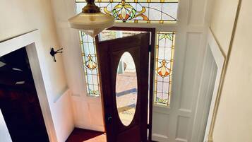 A wooden door with a glass panel, a hanging light fixture, and a stained glass window in the background.