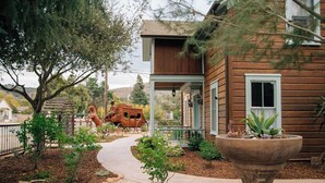 A wooden house with a porch, a garden with a pathway, and a large planter. - 1882 Heritage House ~ Porches, Gardens & Bali Bed (Los Alamos)