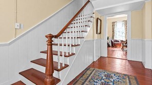 A wooden staircase with white railings leading to a dining area.