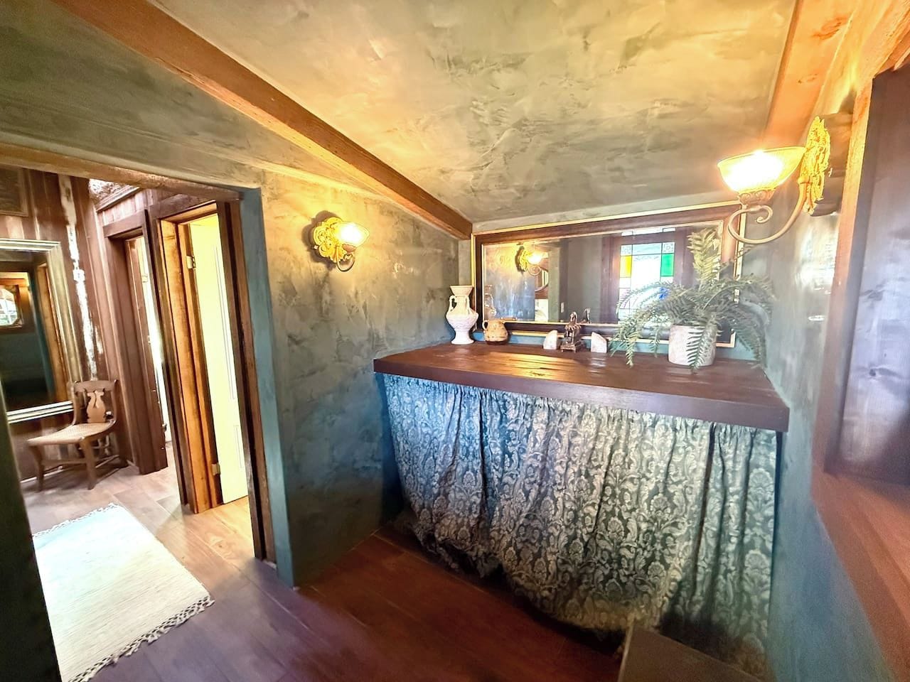 Une salle de bain avec un meuble-lavabo en bois, un miroir et un rideau à motifs.