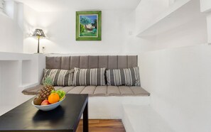 A modern living room with a sofa, a table with fruit, and a painting on the wall.