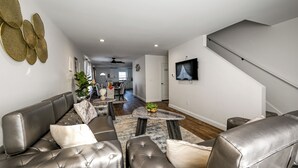 Ein modernes Wohnzimmer mit einer Ledersofa, einem Couchtisch und einem an der Wand befestigten Flachbildfernseher.