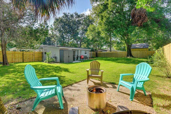 A backyard with a fire pit, two Adirondack chairs, and a wooden fence. - Emerald Coast Home: Outdoor Entertainment Area! (Mary Esther)