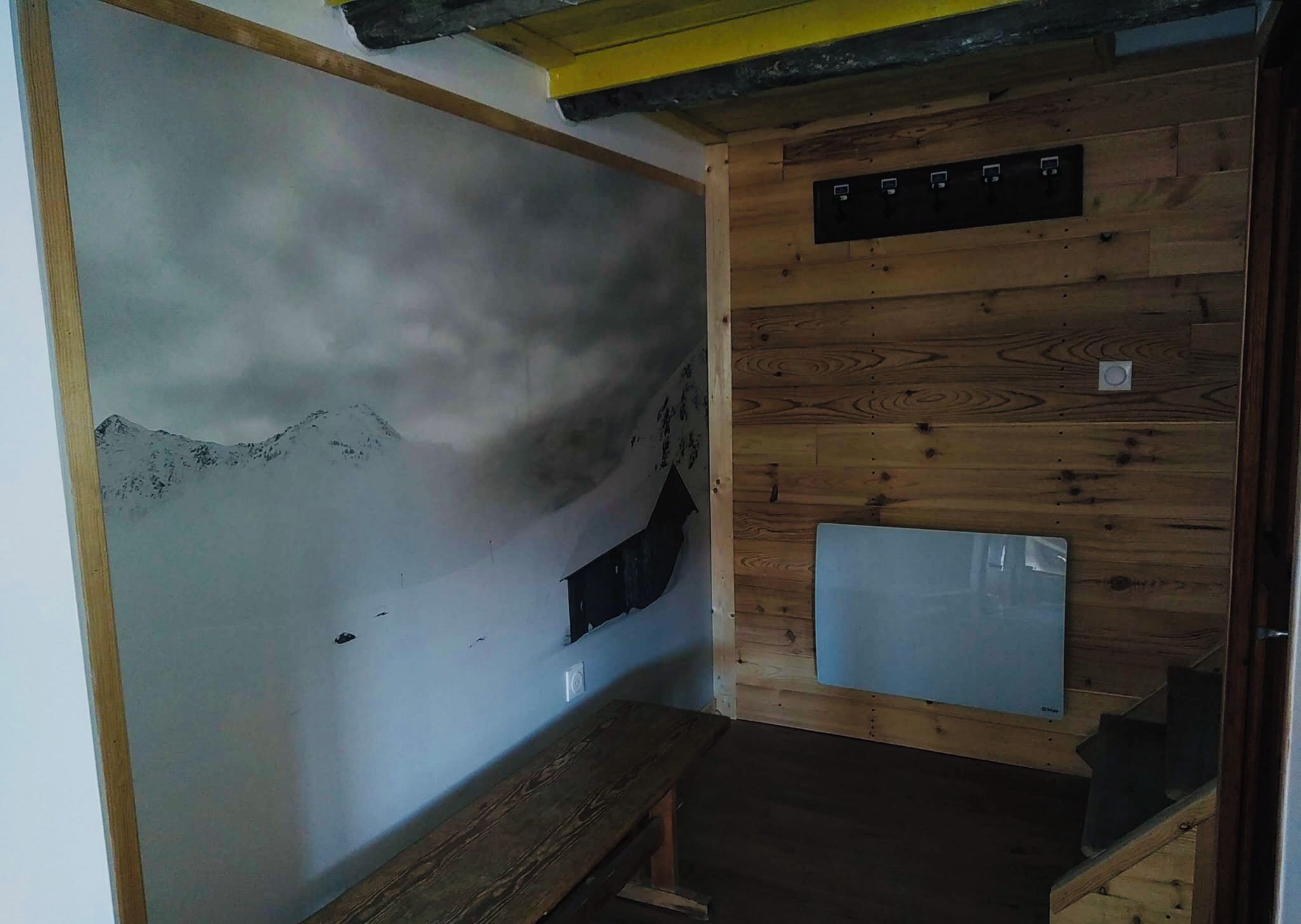 A room with a wooden wall, a small window, and a wooden staircase.
