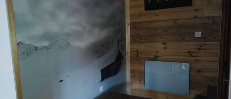 A room with a wooden wall, a small window, and a wooden staircase.