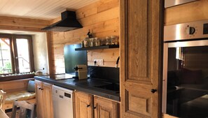 Une cuisine avec des meubles en bois, un plan de travail noir, un four encastré et une fenêtre donnant sur un beau paysage.
