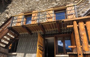 Un chalet doté d’un balcon en bois et d’un mur en pierre.