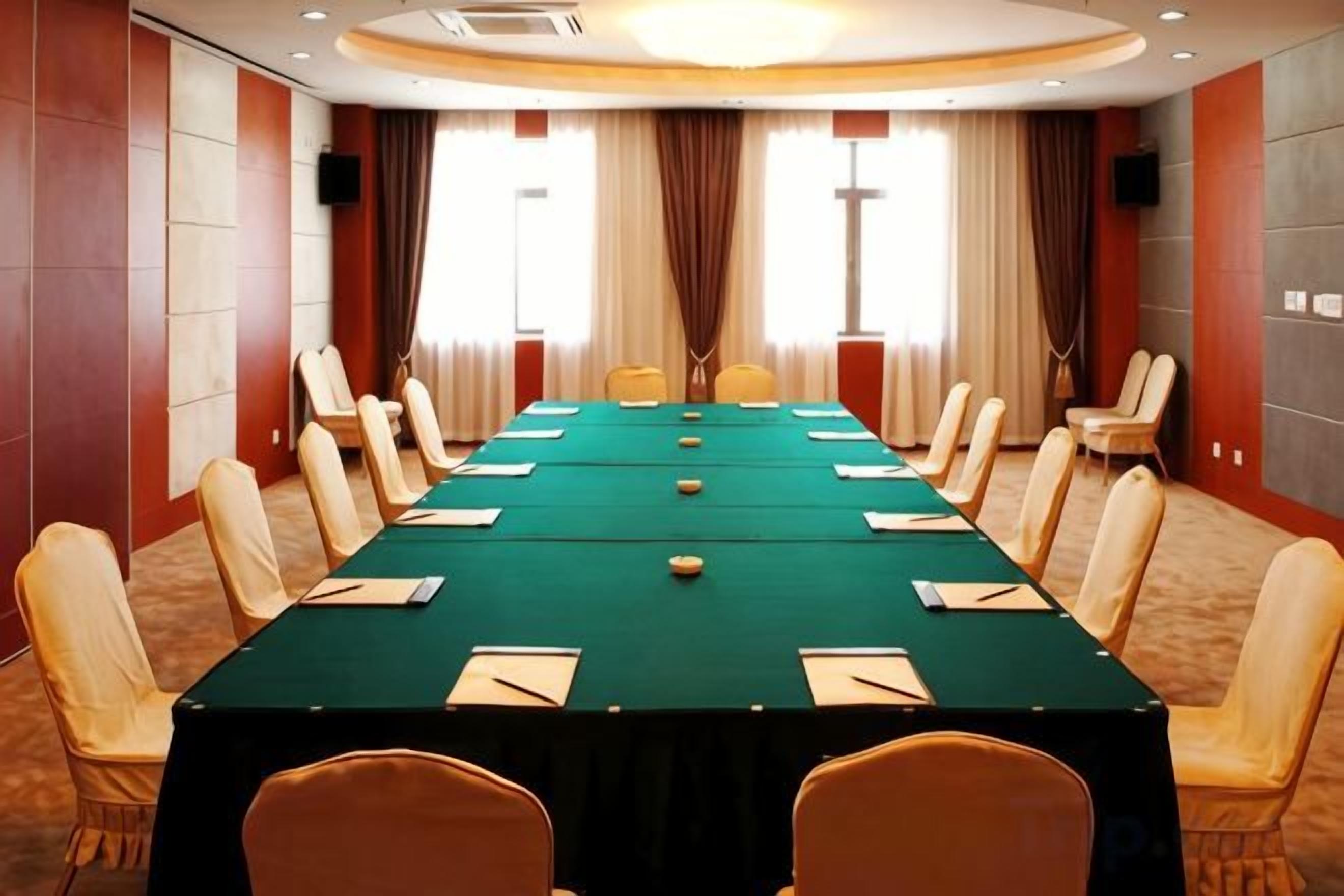 A conference room with a long table, chairs, and a carpeted floor.