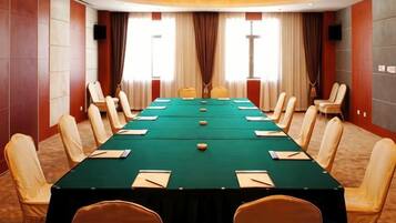 A conference room with a long table, chairs, and a carpeted floor.