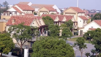 A residential area with houses featuring red-tiled roofs and a central road.