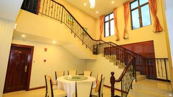 Interior de un hotel de varios niveles con comedor, una escalera y vistas al exterior.