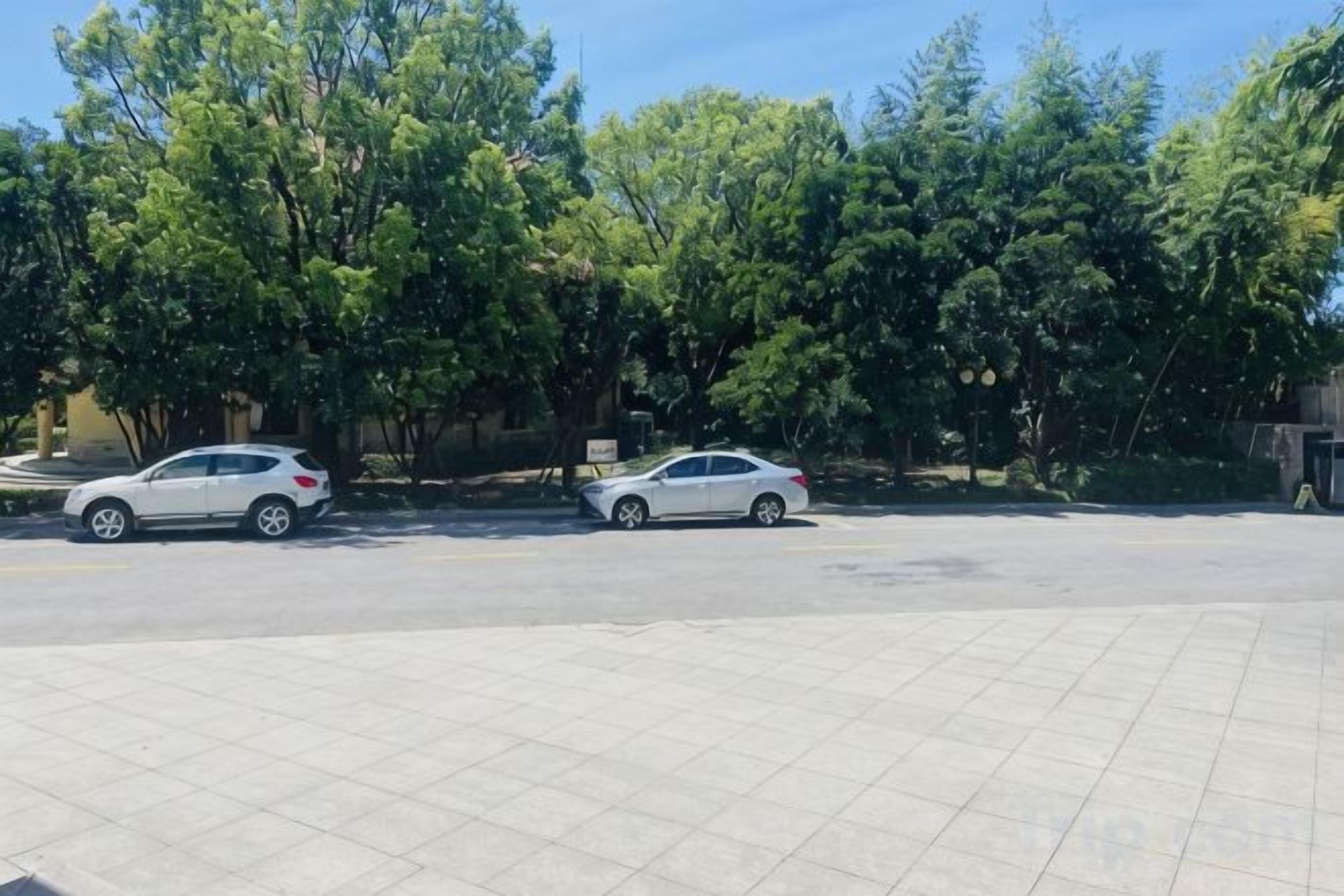 Un estacionamiento con dos coches y un camino pavimentado.