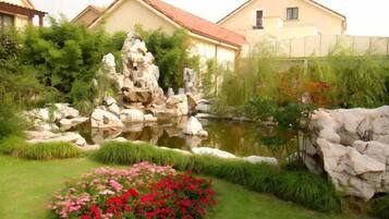 Un jardin avec un étang, des rochers et des fleurs.