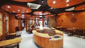 Un restaurante con interiores de madera, una barra central y varias zonas de estar.