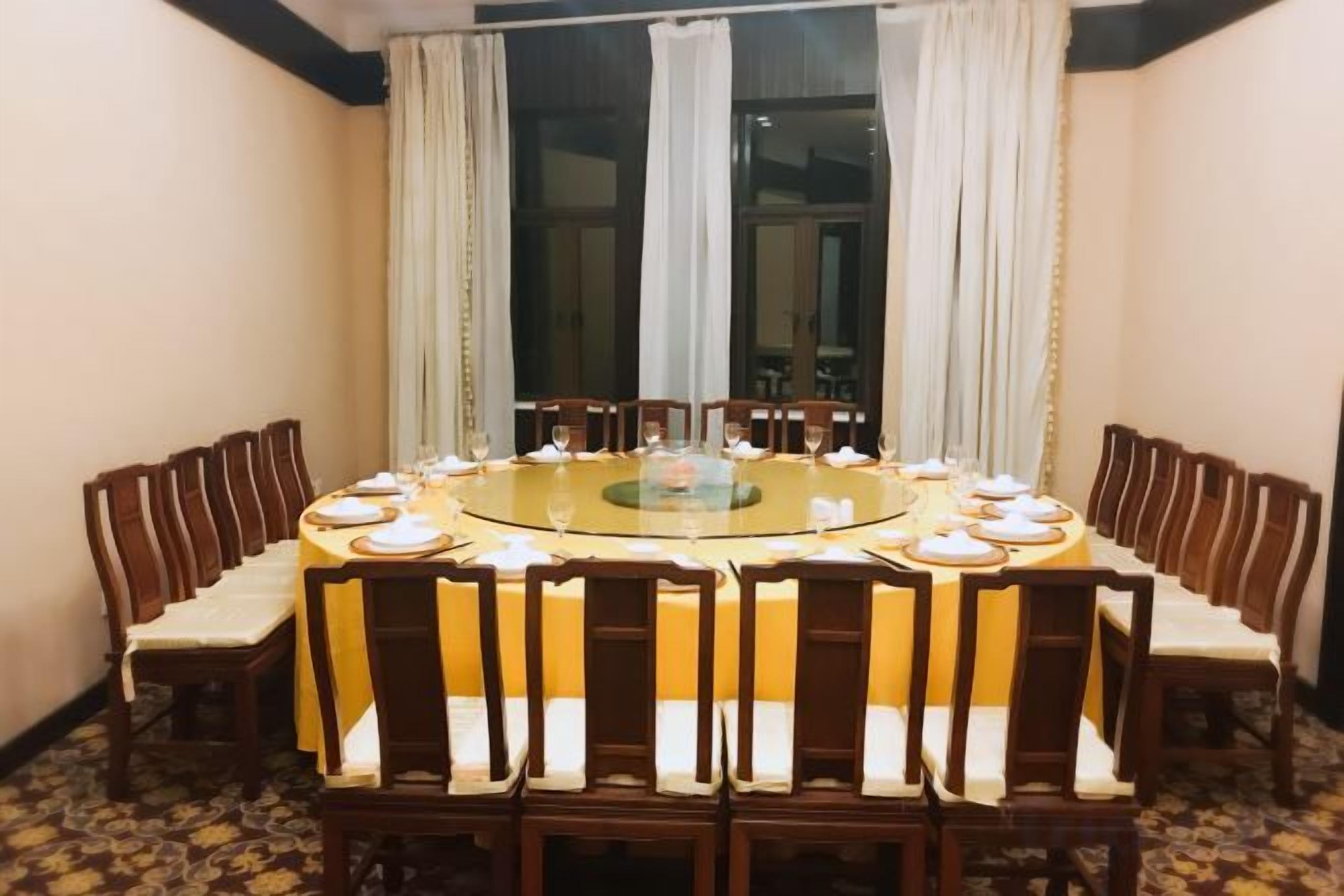 A round dining table with chairs, a central glass-top table, and a carpeted floor.