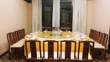 A round dining table with chairs, a central glass-top table, and a carpeted floor.
