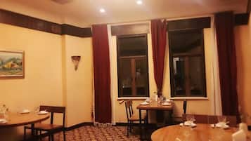 Un comedor con mesas y sillas redondas, un cuadro en la pared y una ventana con cortinas.