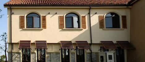 A two-story building with a beige facade, stone accents, and a tiled roof.