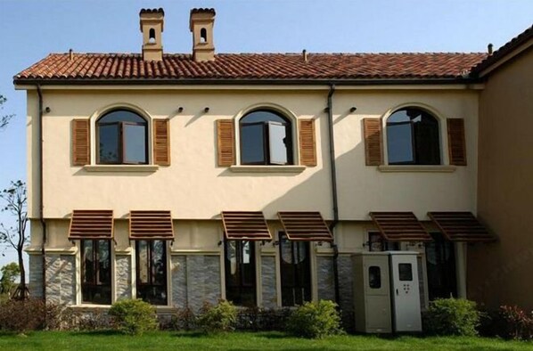 A two-story building with a beige facade, stone accents, and a tiled roof. - Golden Villa Park Hotel Shanghai (Shanghai)