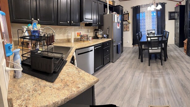 A modern kitchen with dark cabinetry, granite countertops, stainless steel appliances, and a central island with seating. - Charming 3-bedroom house in lovely Howard with AC, WiFi (Howard)
