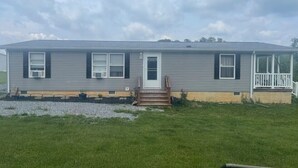 A single-story house with a front porch, a small front yard, and a cloudy sky. - Charming 3-bedroom house in lovely Howard with AC, WiFi (Howard)