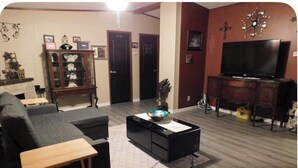 A living room with a sofa, a coffee table, a TV, a cabinet, and a fireplace. - Charming 3-bedroom house in lovely Howard with AC, WiFi (Howard)