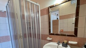 Ein Badezimmer mit Duschkabine, Waschbecken, Spiegel und Toilette.