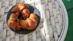 Ein runder Tisch mit gewebter Oberfläche, auf dem eine schwarze Schieferplatte mit drei Croissants steht.
