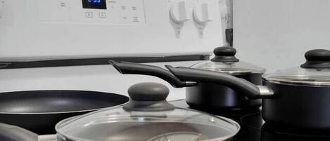 A kitchen with a white stove, black pots, and a digital clock displaying 3:29.