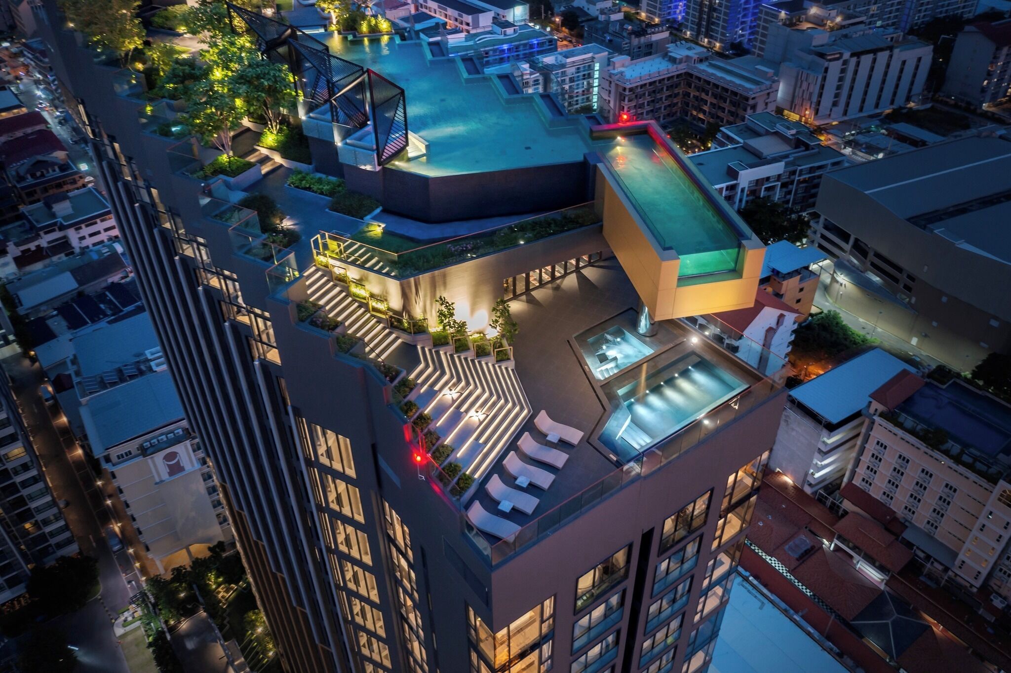 A high-rise building with rooftop terraces, outdoor seating areas, and a swimming pool.