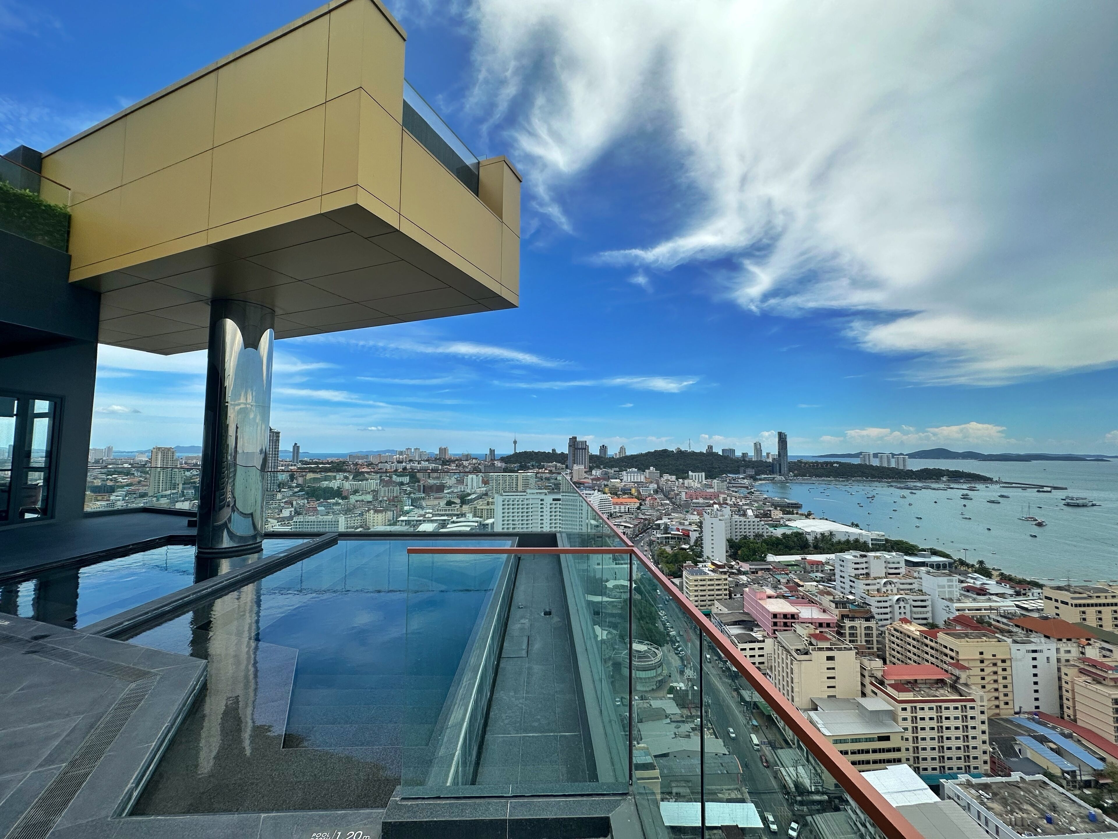 A high-rise building with a glass floor and a view of a cityscape and coastline.