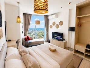 A modern hotel room with a large bed, a television, and a view of the cityscape. - The Edge central pattaya  (Pattaya)